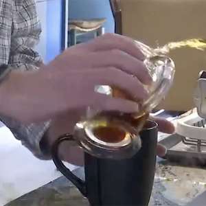 A shaking hand pouring coffee